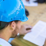 Male construction worker in hard hat looking at construction plans